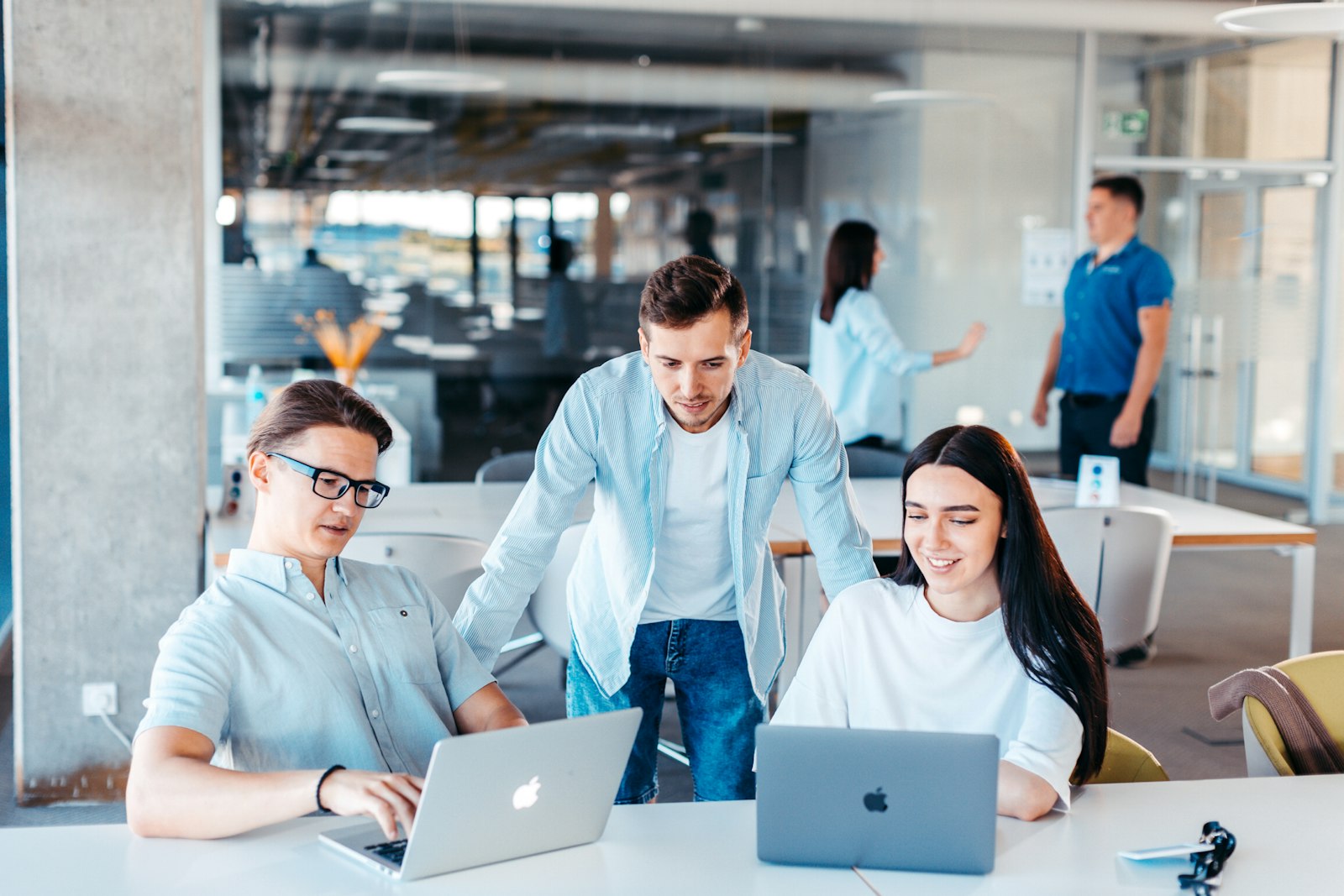 Three colleagues working together at laptops in an office